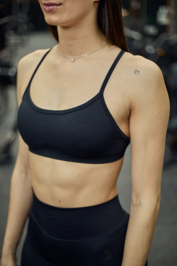 Quore Minimal sports bra in black. Made from high-quality, seamless material. The bra features a special open back design, adjustable straps, and is padded. Wear it to your next workout or outdoor activity.