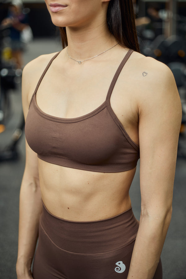 Quore Minimal sports bra in brown. Made from high-quality, seamless material. The bra features a special open back design, adjustable straps, and is padded. Wear it to your next workout or outdoor activity.